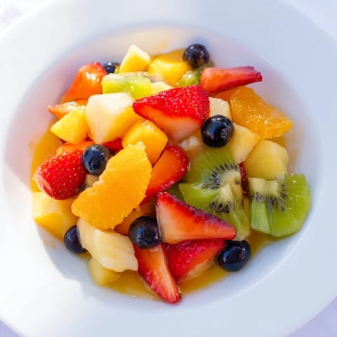 Vibrant fruit salad, a delicious mix of colorful berries and citrus syrup, ready to eat.