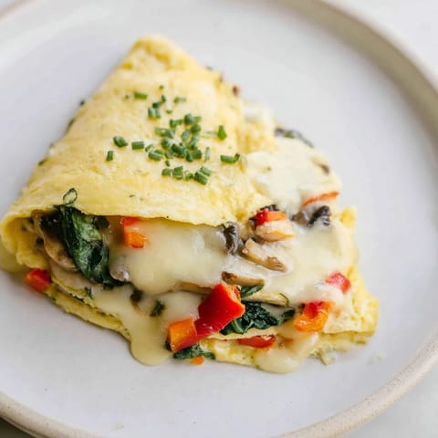 A beautiful photograph of a freshly cooked omelet with cheese, ready to devour on the plate.