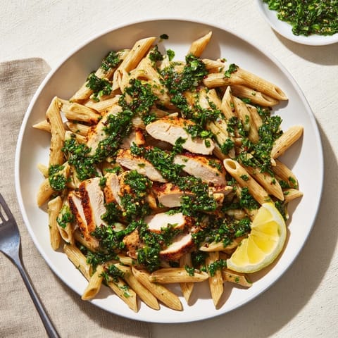 Succulent Chimichurri Chicken Pasta is served with lemon wedges and fresh parsley, offering a zesty, dairy-free main course for family dinners.  