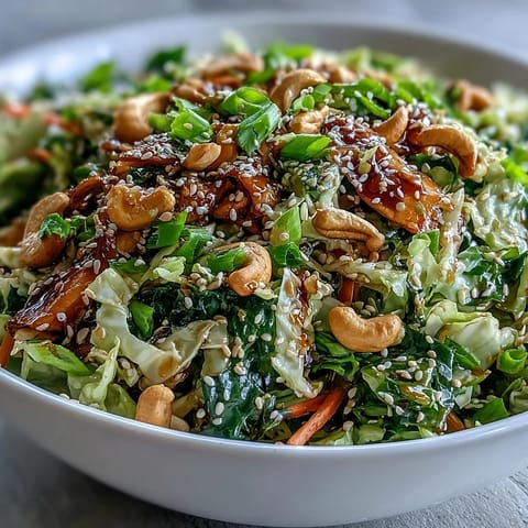 Freshly chopped Asian Cabbage Salad featuring shredded purple cabbage, carrots, and cilantro with a spicy drizzle.