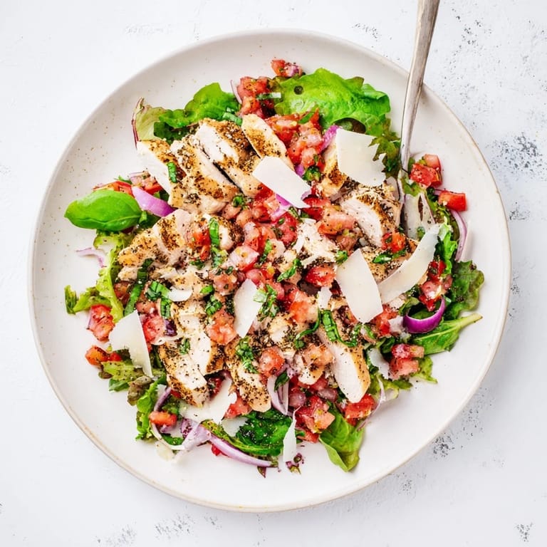 A close-up of juicy Bruschetta Chicken Salad showcasing diced tomatoes, fresh basil, and tender grilled chicken, served with a lemon wedge on the side.