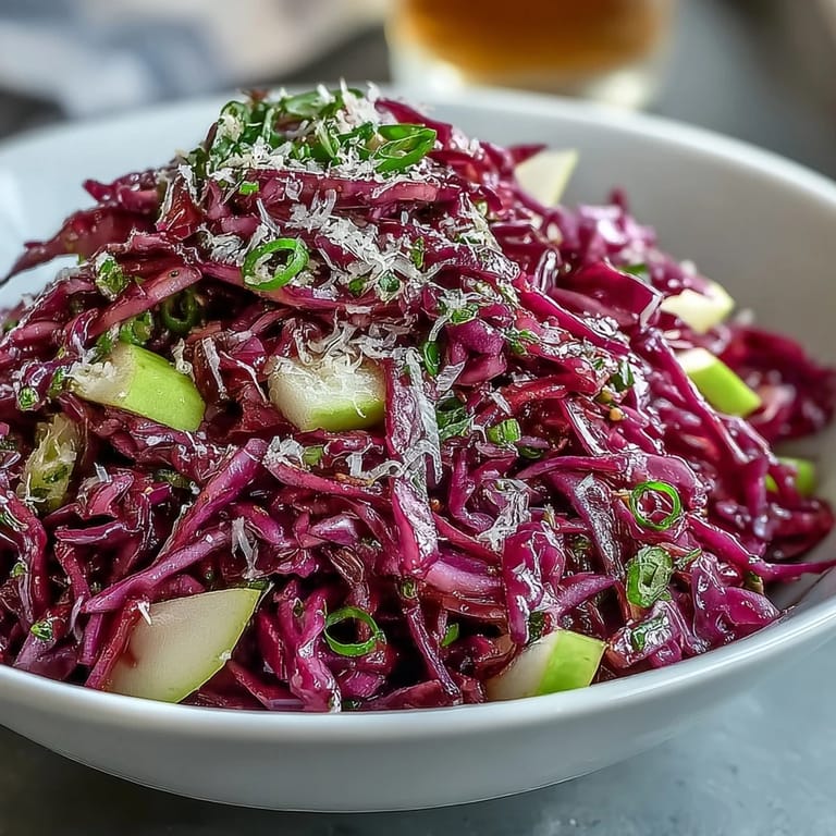 A rustic wooden serving bowl filled with crunchy Red Cabbage Coleslaw, topped with shaved Parmesan and fresh herbs.