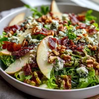 Fresh frisée lettuce topped with sliced ripe pears, crumbled blue cheese, crispy prosciutto, and toasted walnuts, drizzled with vinaigrette.