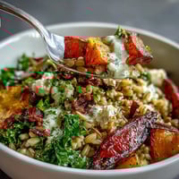 A close-up of a Hearty Winter Grain Bowl with roasted carrots, parsnips, and sweet potatoes on farro and wilted kale.