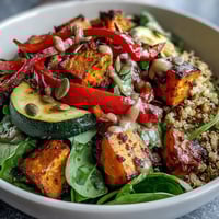 Warm Salad Bowl with roasted sweet potatoes, quinoa, and wilted spinach, drizzled with warm vinaigrette.