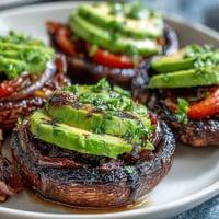 Juicy grilled portobello mushroom burgers loaded with fresh avocado and toppings.